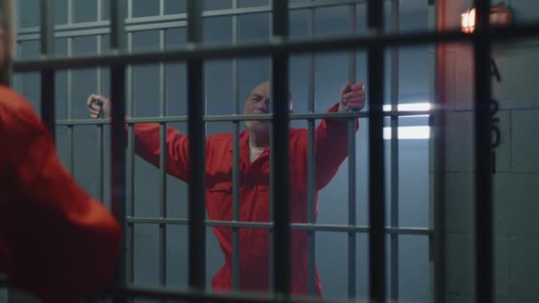 两个有罪的人一起在监狱服刑 老罪犯站在监牢里 手拉手 与邻居交谈 拘留中心或教养所的罪犯 — 图库视频影像