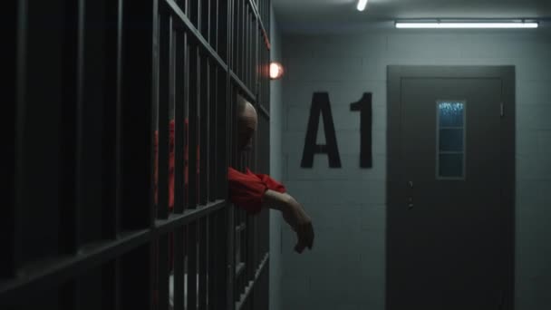 Oudere Gevangene Oranje Uniform Strekt Zijn Handen Uit Leunt Metalen — Stockvideo