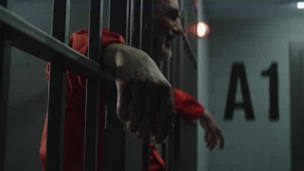 Starší Vězeň Oranžové Uniformě Pláče Drží Ruce Kovových Mřížích Odpykává — Stock video