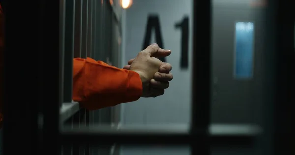 囚人の近くにオレンジの制服を着た金属棒を持って刑務所の独房に立って 有罪の犯罪者または殺人者は 犯罪の懲役刑を言い渡される 刑務所又は拘置所の受刑者 司法制度 — ストック写真