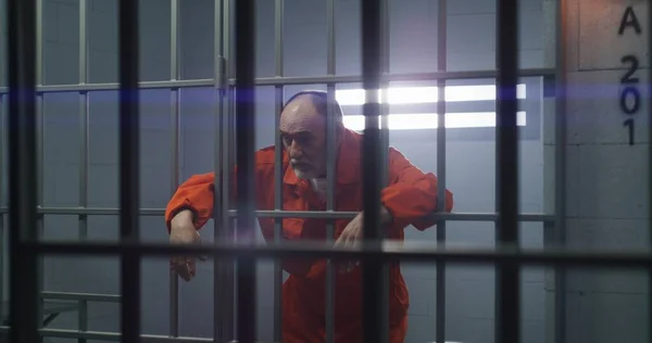 Oudere Gevangene Oranje Uniform Houdt Handen Metalen Staven Kijkt Naar — Stockfoto