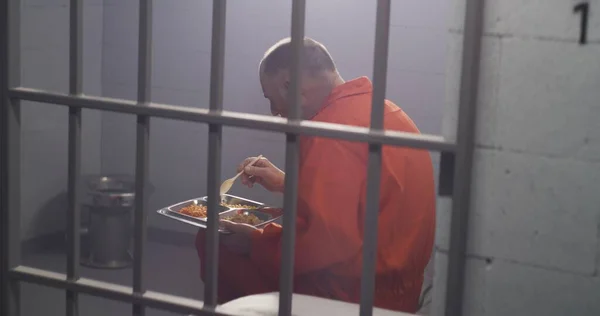 Elderly Prisoner Orange Uniform Sits Prison Cell Eats Dinner Criminal — Stock Photo, Image