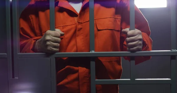 オレンジの制服を着た高齢の囚人は金属棒を持ち 刑務所の独房に立っている 有罪の犯罪者または泥棒は 犯罪の懲役刑の言葉を提供します 刑務所 拘置所又は矯正施設の受刑者 — ストック写真