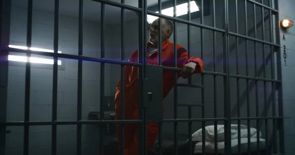 Oudere Gevangene Oranje Uniform Leunt Handen Metalen Staven Crimineel Zit — Stockfoto