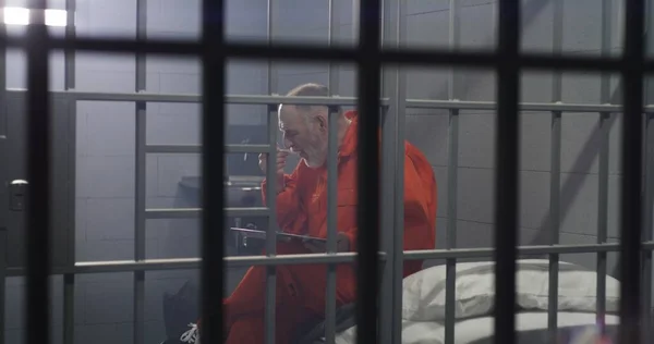 Turuncu Üniformalı Yaşlı Mahkum Hapishane Hücresinde Oturup Yemek Yiyor Suçlu — Stok fotoğraf