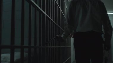 Polis coplu bir hapishane çalışanı hapishane hücrelerinde suçluları izliyor. Turuncu üniformalı mahkumlar demir parmaklıklar arkasında duruyor, hapiste hapis yatıyorlar. Gözaltı merkezi ya da ıslah evi.