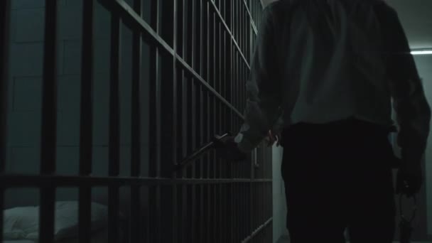 监狱工作人员拿着警棍在监牢里监视罪犯 身穿橙色制服的囚犯站在铁窗后 在狱中服刑 拘留中心或教养所 — 图库视频影像