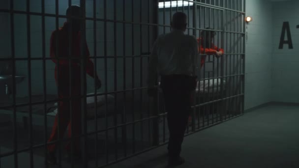 狱警拿着警棍监视着监牢里的罪犯 身穿橙色制服的囚犯因在狱中犯罪而被判处监禁 在拘留中心或教养所工作 — 图库视频影像