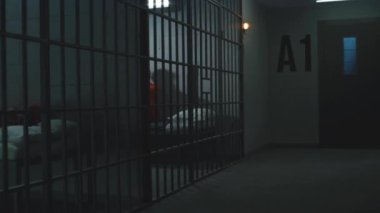 Turuncu üniformalı suçlular hapishane hücrelerindeki yataklara uzanıp otururlar. Hapiste işlenen suçlardan dolayı iki mahkum hapis cezasına çarptırıldı. Gözaltı merkezinde ya da cezaevinde depresyonda olan mahkumlar.