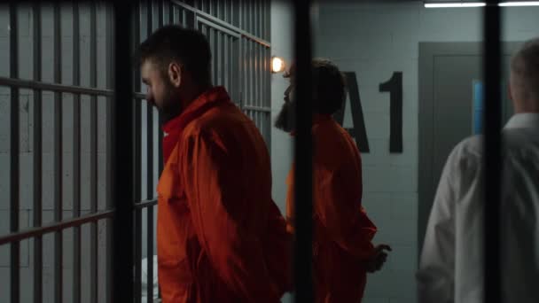 Deux Prisonniers Uniforme Orange Font Face Des Barreaux Métalliques Devant — Video