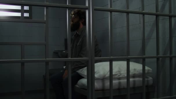 Guilty Criminal Sits Bed Prison Cell Looks Barred Window Prisoner — Stock Video