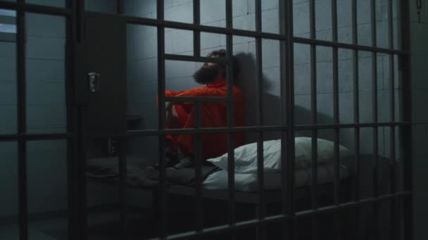 Vinný Zločinec Oranžové Uniformě Sedí Posteli Vězeňské Cele Zamřížovaným Oknem — Stock video