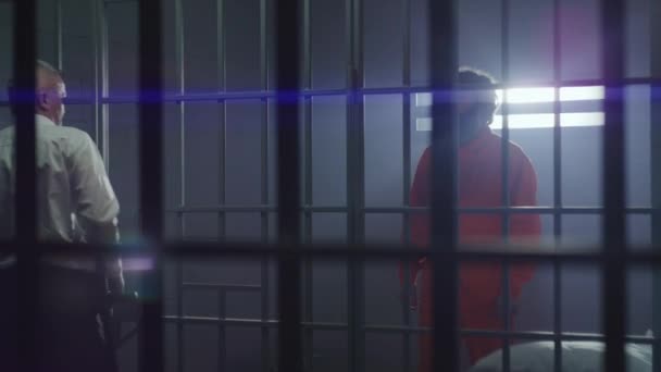 Gevangenismedewerker Geeft Telefoon Aan Mannelijke Crimineel Metalen Tralies Gevangene Oranje — Stockvideo