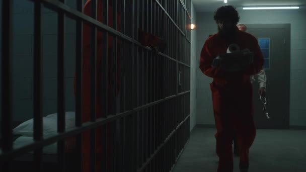 狱卒带着身穿橙色制服的罪犯进了监狱 沮丧的囚犯面对铁条站在那里 走进去 囚犯在拘留中心或教养所服刑 — 图库视频影像