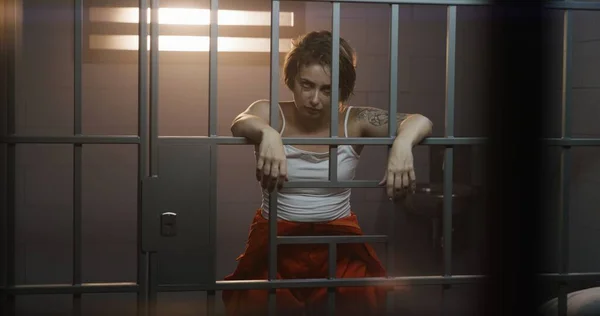 Female Prisoner Orange Uniform Holds Hands Bars Stands Jail Cell — Stock Photo, Image