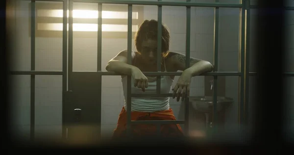 Female Prisoner Orange Uniform Holds Hands Bars Stands Jail Cell — Stock Photo, Image