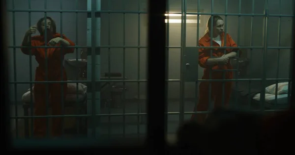 Dvě Ženy Oranžových Uniformách Vstanou Jdou Mříže Vězeňské Cele Zločinci — Stock fotografie