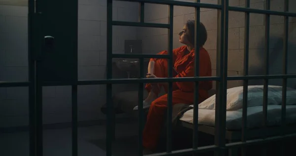 Deprimerad Kvinnlig Fånge Intern Orange Uniform Sitter Sängen Fängelsecell Kvinnlig — Stockfoto
