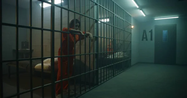 Eine Gefangene Orangefarbener Uniform Steht Hinter Metallgittern Eine Andere Sitzt — Stockfoto