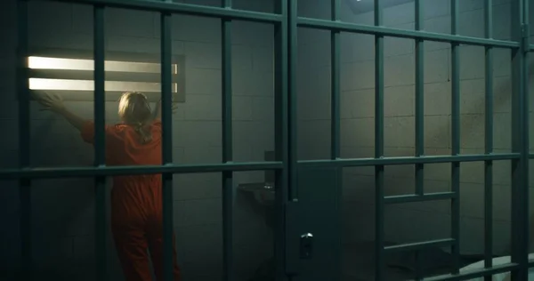 Female Prisoner Orange Uniform Walks Jail Cell Looks Barred Window — Stock Photo, Image