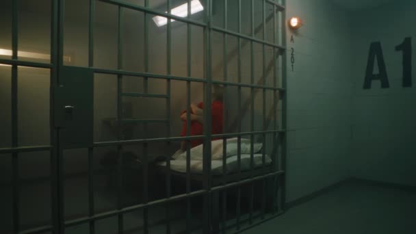 Dolly Shot Female Prisoner Orange Uniform Sitting Bed Jail Cell — Αρχείο Βίντεο