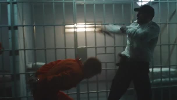 身穿橙色制服的囚犯与狱卒打斗 另一个罪犯勒死了监狱官员 并将手铐从狱友身上摘下来 从监狱逃跑 拘留中心或惩教设施内的战斗 — 图库视频影像