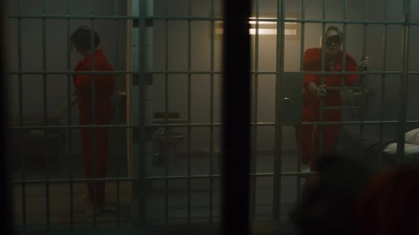 오렌지 제복을 공격적 재소자가 재소자에게 소리를 지르고 쇠창살을 감옥에 넣는다 — 비디오
