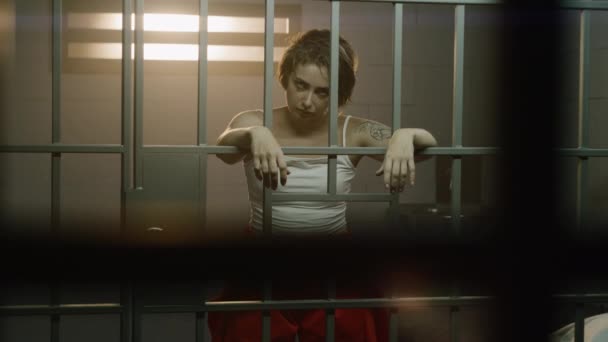 Female Prisoner Orange Uniform Holds Hands Bars Stands Jail Cell — Stock Video