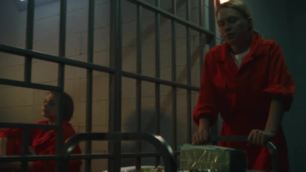 身穿橙色制服的妇女向监狱里的囚犯提供从服务推车到食物 女性罪犯坐在床上 因犯罪服刑 监狱或教养所 — 图库视频影像