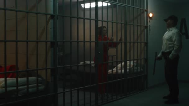 Тюремщик Полицейской Дубинкой Стоит Возле Тюремной Камеры Разговаривает Заключенной Оранжевой — стоковое видео