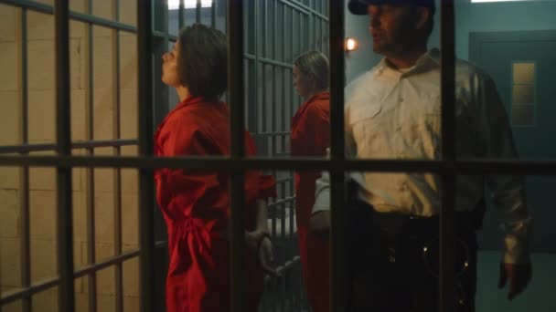Female Prisoners Inmates Orange Uniforms Stand Facing Metal Bars Front — Stockvideo