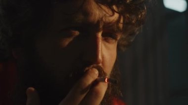 Turuncu üniformalı depresyondaki erkek mahkum hapishane hücresinde oturup sigara içiyor. Tecrit edilmiş suçlu, hapiste suçtan hapis yatıyor. Islah evi. Adalet sistemi. Kapat..