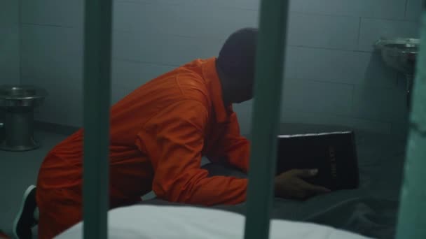 Religioso Prisionero Afroamericano Uniforme Naranja Arrodilla Cerca Cama Reza Dios — Vídeos de Stock