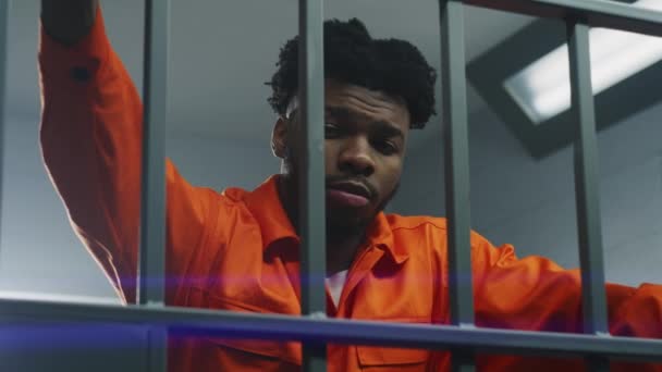 Afroamerikaner Orangefarbener Uniform Lehnt Die Hände Gefängniszellen Und Blickt Die — Stockvideo