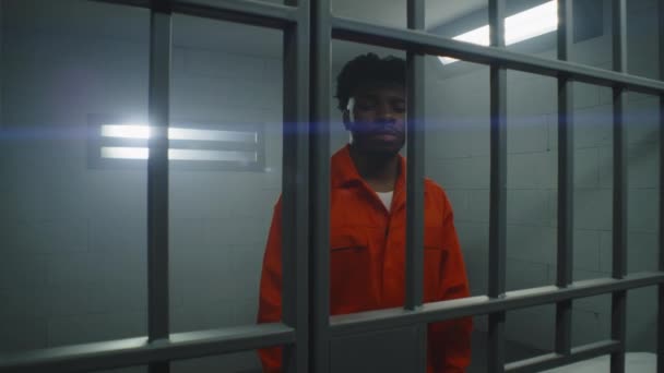 Afrikansk Amerikansk Fånge Orange Uniform Står Bakom Fängelsecellen Och Tittar — Stockvideo