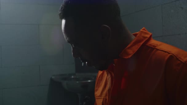Афроамериканский Заключенный Оранжевой Форме Читает Библию Тюремной Камере Переворачивает Страницы — стоковое видео