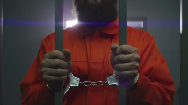 Muž Oranžové Uniformě Poutech Drží Kovové Mříže Stojí Vězeňské Cele — Stock video