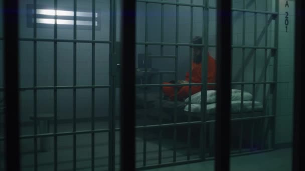 Manlig Fånge Orange Uniform Sitter Sängen Läser Bibeln Fängelsecell Kriminella — Stockvideo