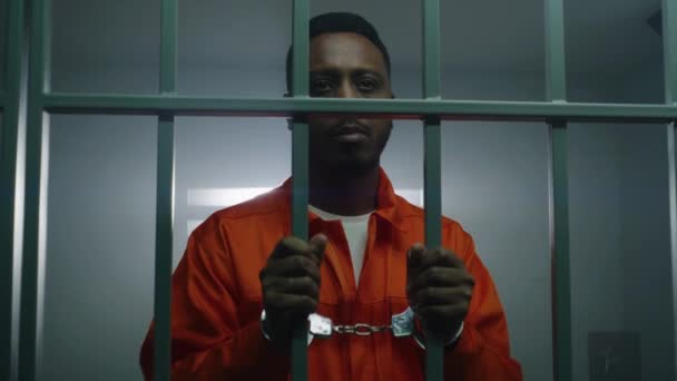 Afrikansk Amerikansk Fånge Orange Uniform Håller Händerna Handbojor Fängelsets Cellstänger — Stockvideo