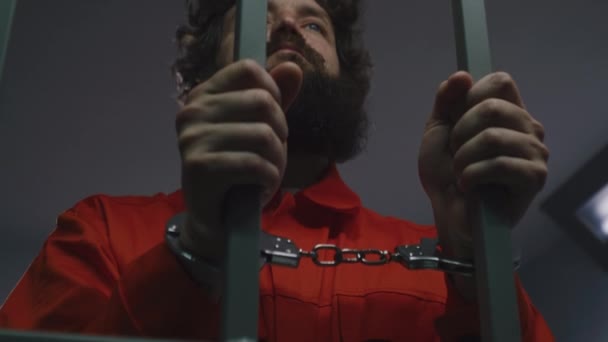 Κρατούμενος Πορτοκαλί Στολή Και Χειροπέδες Κρατά Μεταλλικές Μπάρες Στέκεται Στο — Αρχείο Βίντεο