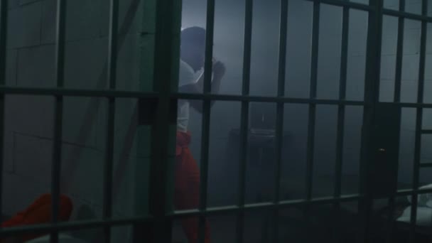 Manlig Afroamerikansk Fånge Orange Uniform Gör Skuggboxning Fängelsecell Fångvaktaren Går — Stockvideo