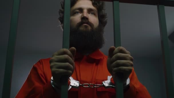Muž Oranžové Uniformě Drží Kovové Mříže Stojí Vězeňské Cele Poutech — Stock video