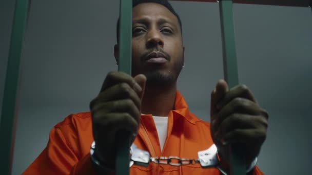 Prigioniero Afroamericano Uniforme Arancione Tiene Mani Manette Sulle Sbarre Delle — Video Stock