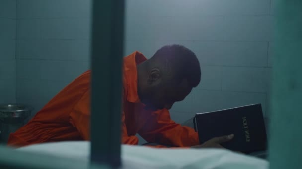 Prigioniero Afroamericano Religioso Uniforme Arancione Inginocchia Vicino Letto Prega Dio — Video Stock
