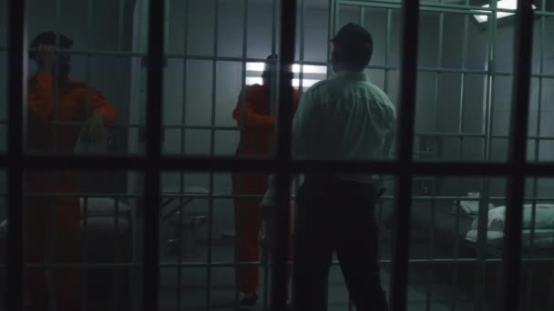 手持警棍的狱卒站在监牢前与囚犯交谈 非裔美国人罪犯在狱中服刑 惩教设施或拘留中心的杀人犯 — 图库视频影像