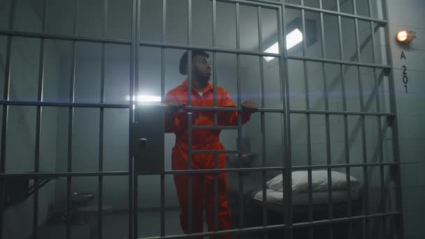 Afro Amerikaanse Gevangene Oranje Uniform Leunt Cel Bars Kijkt Rond — Stockvideo