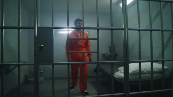 Афро Американский Заключенный Оранжевой Форме Смотрит Закрытое Окно Опирается Тюремные — стоковое видео