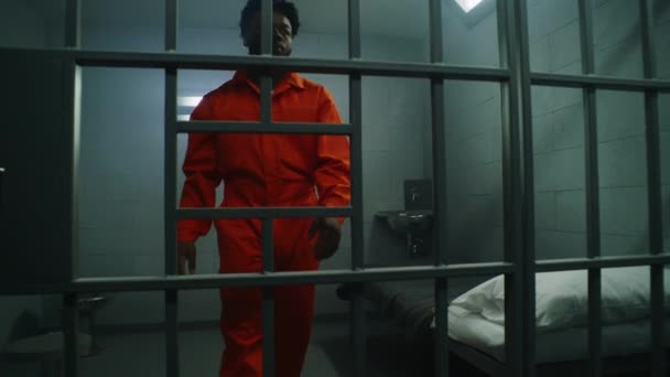Prisonnier Afro Américain Uniforme Orange Regarde Fenêtre Barrée Penche Sur — Video