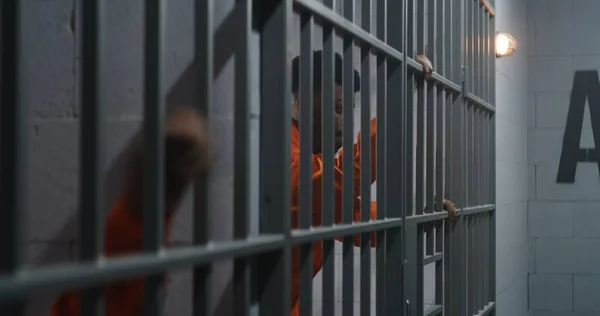 Africký Zajatec Oranžové Uniformě Opírá Vězeňské Mříže Sousední Zločinec Vyčnívá — Stock fotografie