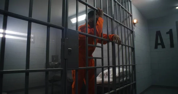 Prigioniero Afroamericano Uniforme Arancione Appoggia Alle Sbarre Delle Celle Criminale — Foto Stock